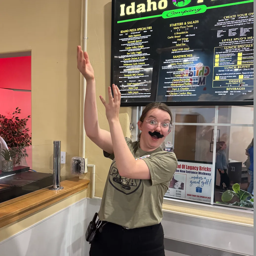 A Children's Museum of Idaho staff moment behind an Idaho Café menu.
