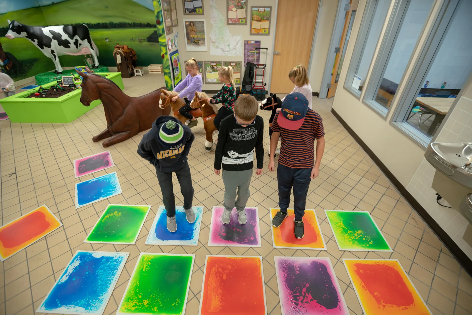Kids playing on the interactive liquid floor tiles near the Indoor Farm exhibit.