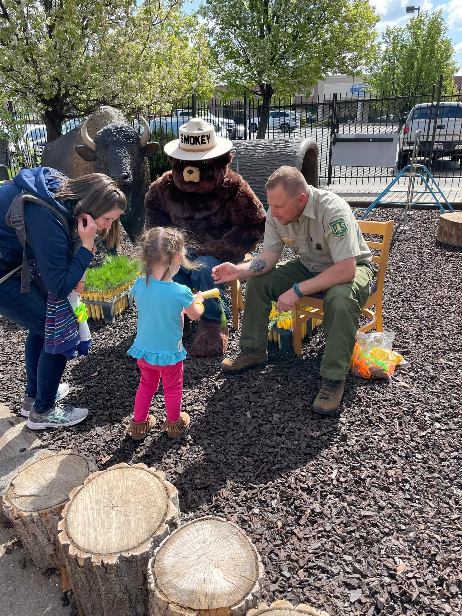 Smokey Bear visits the museum, greeting a child during a forest ranger community partnership event.