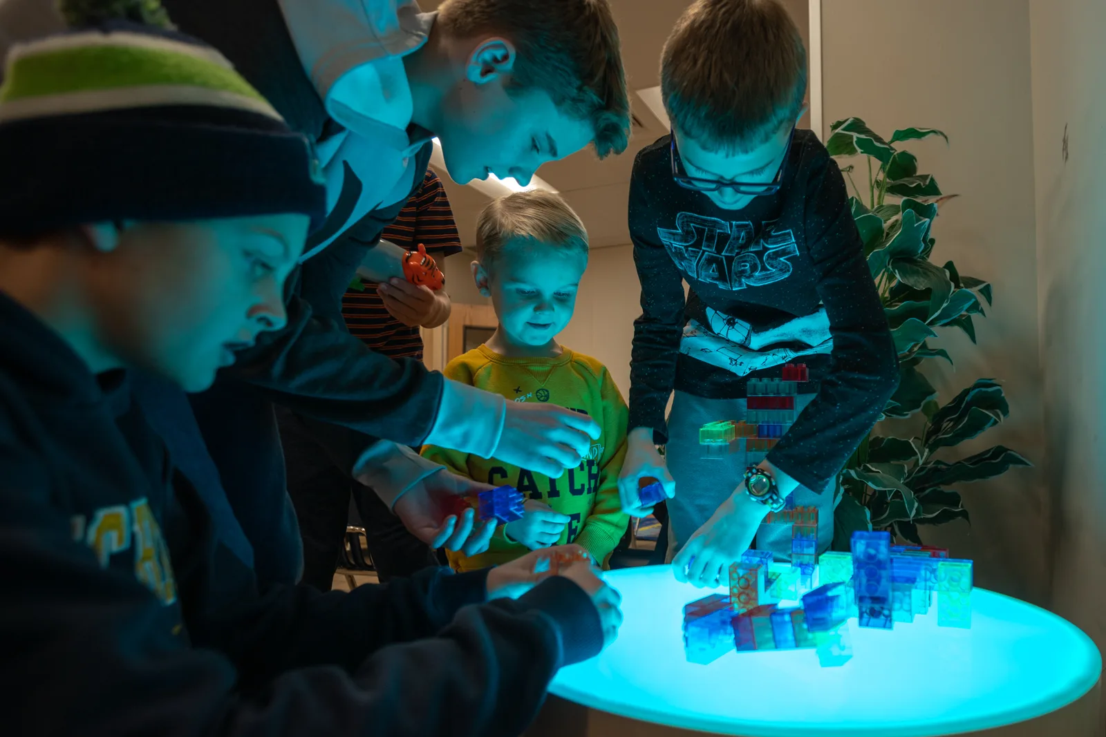 Kids playing with colored blocks on a glowing light table.