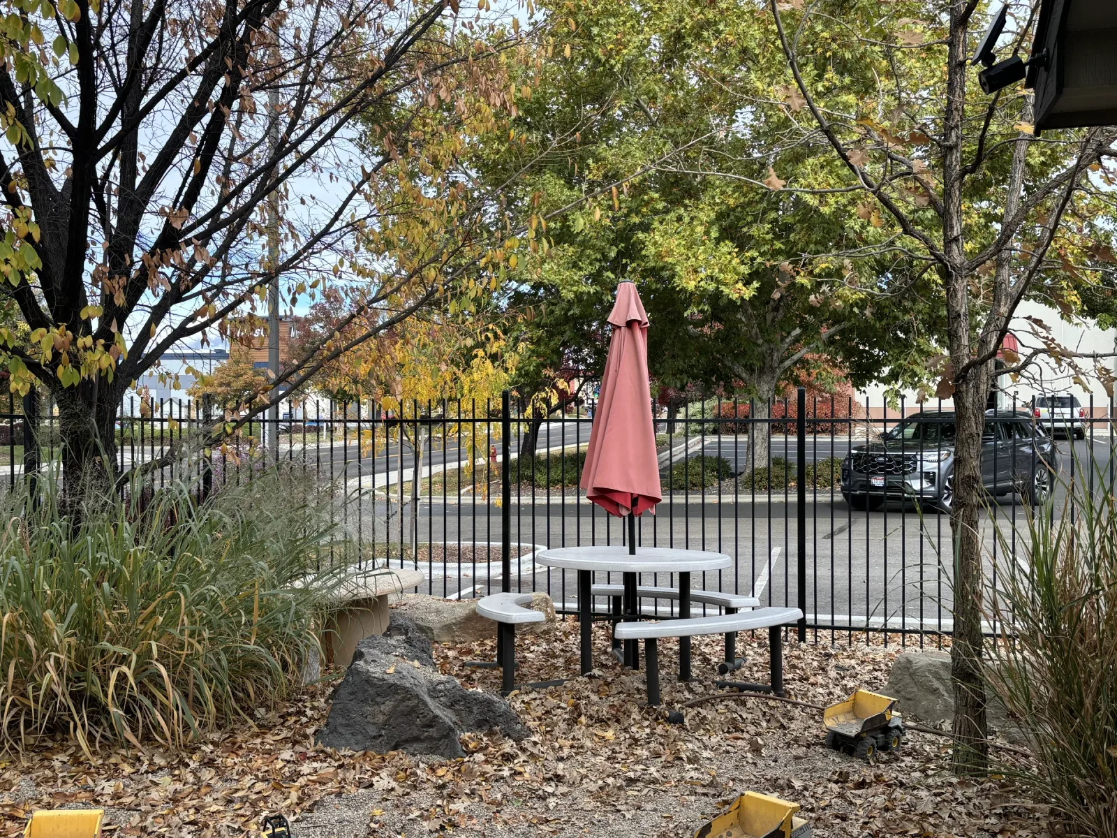 A round table with an umbrella beside the fence in the museum's outdoor area.