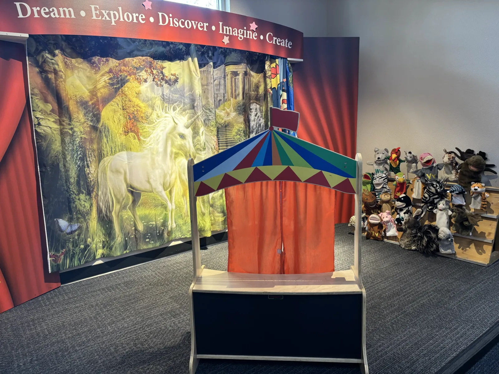 The Children's Theater stage, with a puppet booth in front of a painted curtain and a shelf of puppets.
