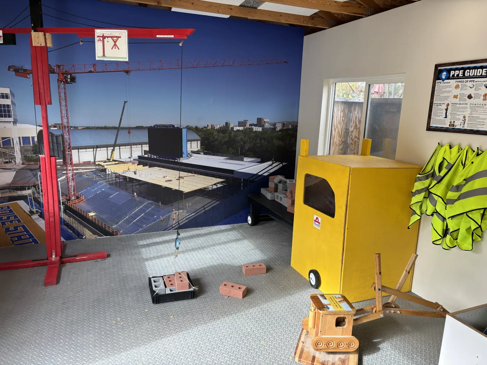 The Builder's Workshop: a construction-site mural with a crane, a yellow cart, toy bricks and hi-vis vests.